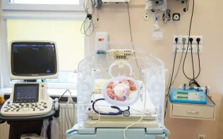 Noworodek leżący w inkubatorze na oddziale neonatologii szpitala Salve