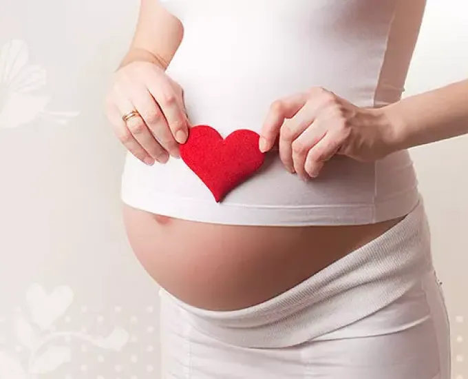 Kobieta w ciąży trzymająca serce na brzuchu