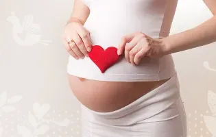 Kobieta będąca w ciąży trzymająca serce na brzuchu
