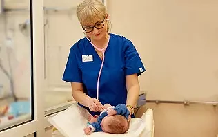 Położna badająca noworodka na oddziale położniczym w szpitalu Salve