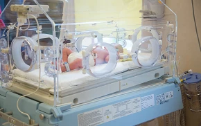 Noworodek leżący w inkubatorze na oddziale neonatologii w szpitalu Salve