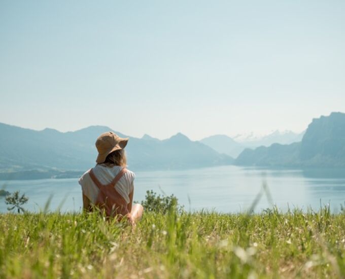 girl-with-had-sitting-green-lawn-near-lake.jpg